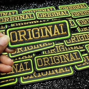 May include: A pile of black and green iron-on patches with gold embroidery that reads "ORIGINAL".