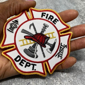 Op de afbeelding: Een witte geborduurde patch met een rood, geel en zwart brandweerlogo. De patch toont een brandweerhelm, een bijl, een ladder en een brandkraan. De tekst "FIRE DEPT." is in zwart op de patch geborduurd.