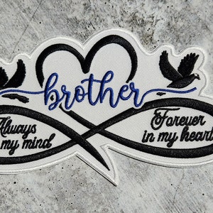 Puede incluir: Parche bordado en blanco y negro con un símbolo de infinito y dos palomas. El texto "hermano" está en letra cursiva azul. El símbolo de infinito tiene el texto "Siempre en mi mente" en un lado y "Para siempre en mi corazón" en el otro.