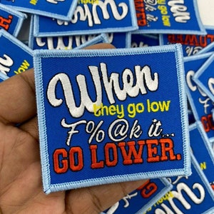 May include: A blue embroidered patch with white text that reads "When they go low F%@k it... GO LOWER."