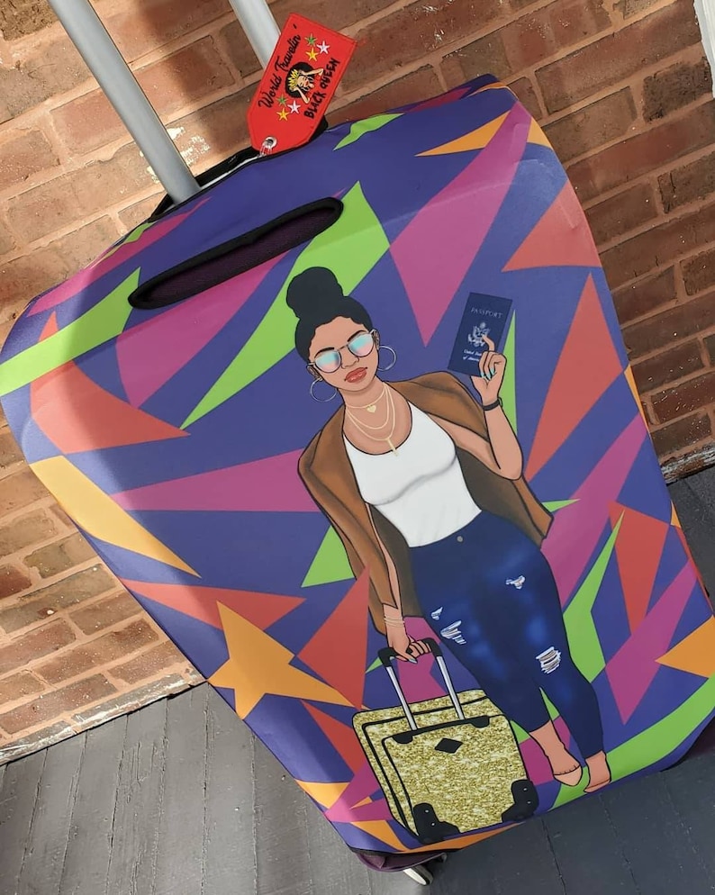 Puede incluir: Una funda de equipaje de color morado, verde, naranja y amarillo con una ilustraci&oacute;n de dibujos animados de una mujer que lleva una chaqueta marr&oacute;n, una camisa blanca, unos vaqueros azules y gafas de sol. La mujer lleva un pasaporte y una maleta dorada. La funda de equipaje tiene una etiqueta que dice "World Traveler" y "Black Owned".