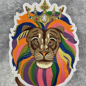 Puede incluir: Parche bordado de la cabeza de un león con una melena arcoíris y una corona dorada. El león tiene un pelaje marrón y una expresión seria.