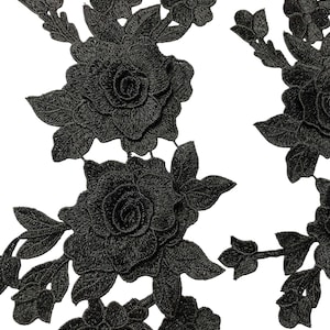 May include: Black embroidered floral applique featuring roses and other flowers with detailed leaves. The applique is made of a textured fabric, suitable for embellishing clothing, accessories, or home decor projects.