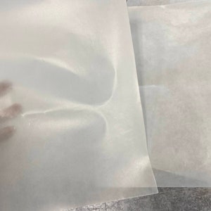 May include: Two sheets of white parchment paper, one on top of the other. The top sheet is slightly creased.