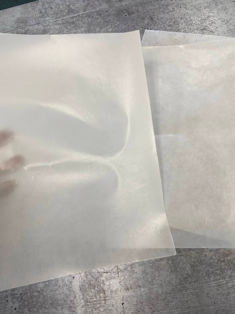 May include: Two sheets of white parchment paper, one on top of the other. The top sheet is slightly creased.