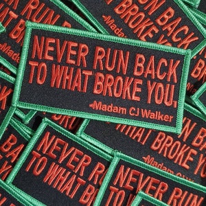 May include: Close-up of several black fabric patches with green stitching. The patches have the text "Never Run Back To What Broke You." in red lettering. The text "Madam CJ Walker" is also included on some of the patches.