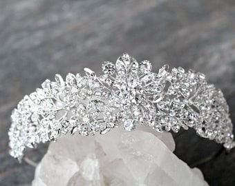 May include: Silver bridal tiara with a floral design and clear rhinestones.