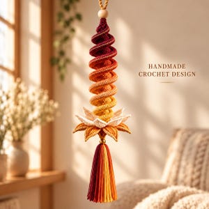 May include: A hanging crochet ornament featuring a spiral column that transitions from deep red to orange and yellow. Below the spiral is a white and orange lotus flower, finished with a multi-colored tassel. Text reads: HANDMADE CROCHET DESIGN.