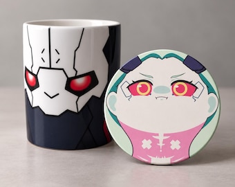 May include: A ceramic mug and a matching circular lid. The mug features a white and black robotic mask design with glowing red eyes. The lid displays a cartoon character with teal hair, yellow eyes, and a pink outfit with white cross details.