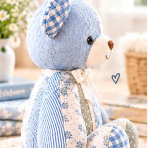 May include: A stuffed bear toy featuring a patchwork design of blue and white fabrics. The bear has a blue gingham ear, a cream-colored muzzle with a brown nose, and a cream ribbon tied around its neck. The body displays floral and striped patterns.