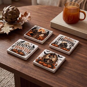 May include: Four square ceramic coasters featuring Halloween-themed illustrations. One shows a skeleton in a top hat, another says "Happy Haunting" with a house, one says "Haunted Harvest" with pumpkins, and the last depicts a spooky forest scene.