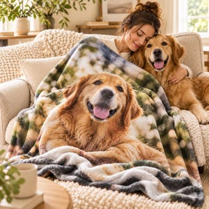 May include: A soft, plush throw blanket featuring a large, high-definition photographic print of a golden retriever with its tongue out, set against a blurred, sunlit background of white flowers and green foliage, draped over a textured sofa.