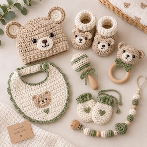 Puede incluir: Un conjunto de bebé de ganchillo que incluye un gorro de oso color canela con orejas, patucos a juego, un babero crema con borde festoneado verde y cara de oso, un sonajero, manoplas y un clip para chupete con cuentas de madera.