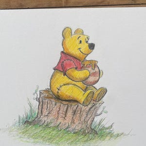 May include: A colored pencil drawing on white paper featuring a yellow bear wearing a red shirt, sitting on a brown tree stump. The bear is holding a round, tan-colored honey pot with visible drips. Green grass is drawn at the base of the stump.