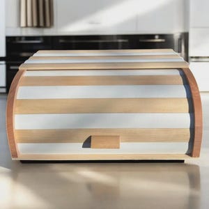Peut inclure: Une boîte à pain dotée d'un couvercle coulissant avec des lattes horizontales alternées en bois naturel clair et en finition blanc mat. Les panneaux latéraux incurvés sont en bois massif et une petite poignée rectangulaire est centrée.