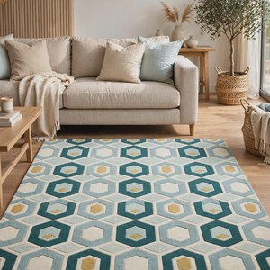 May include: A rectangular area rug featuring a repeating geometric pattern of interlocking hexagons in shades of teal, light blue, cream, and mustard yellow. The design consists of thick borders and solid centers arranged in a structured grid layout.