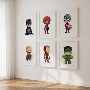 Może przedstawiać: Sześć oprawionych grafik ściennych z ilustracjami superbohaterów w stylu chibi. Postacie to Batman, Spider-Man, Kapitan Ameryka, Thor, Iron Man i Hulk, każda w białej ramce na tle gładkiej, białej ściany.