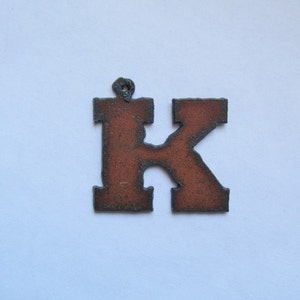 May include: A rusty brown metal letter K ornament. The letter is in a simple, blocky font.