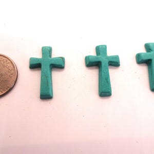 May include: Three turquoise blue cross charms, each about the size of a US quarter.
