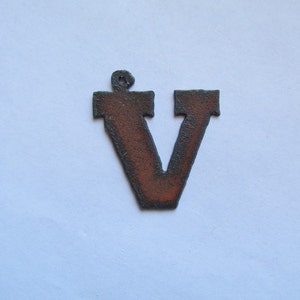 May include: A rusty metal letter V with a slightly rounded top. The letter is a dark brown color with a hint of orange.