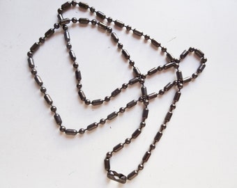 May include: A silver chain necklace with a series of small, round, and cylindrical links.