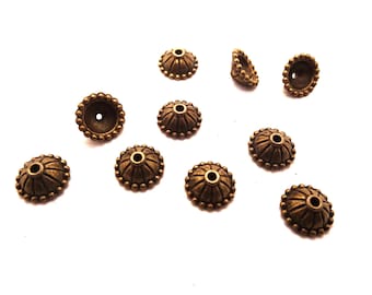 May include: Ten antique gold-toned metal bead caps with a decorative design. The caps are round with a raised center and a beaded edge.