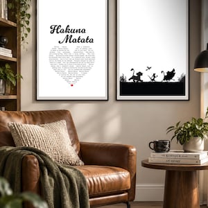 May include: Two framed wall art prints with black frames. The left print features the text Hakuna Matata in black script above a heart-shaped block of text and a small red heart. The right print shows a black silhouette of three characters walking.