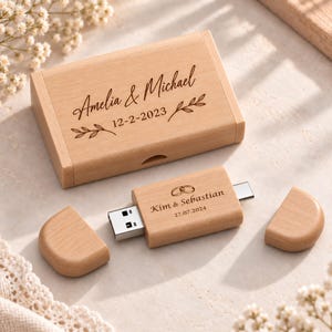 Może przedstawiać: Prostokątne drewniane pudełko i pasująca drewniana pamięć USB z dwiema zdejmowanymi zatyczkami. Pudełko jest wygrawerowane napisami "Amelia & Michael" i "12-2-2023" z motywami liści. Pamięć USB zawiera napisy "Kim & Sebastian" i "27.07.2024".
