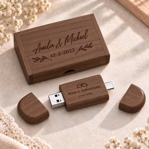 May include: A rectangular dark wood box engraved with the names Amelia & Michael, the date 12-2-2023, and leaf accents. Beside it lies a dark wood USB flash drive engraved with two rings, the names Kim & Sebastian, and the date 27.07.2024.