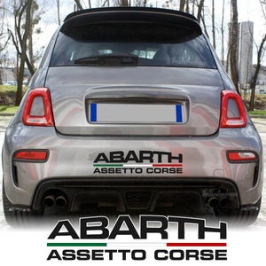 Peut inclure: Vue arrière d'une voiture grise avec un autocollant noir Abarth Assetto Corse sur le pare-chocs. L'autocollant affiche le texte Abarth en lettres noires grasses au-dessus d'une bande horizontale verte, blanche et rouge, avec Assetto Corse.