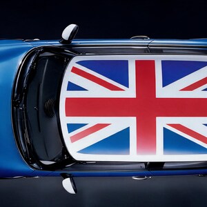 Puede incluir: Una vista cenital de un coche azul que presenta un diseño prominente de la bandera Union Jack en el techo. El vehículo tiene una carrocería de formas redondeadas, espejos laterales blancos y un alerón trasero con un gráfico llamativo.