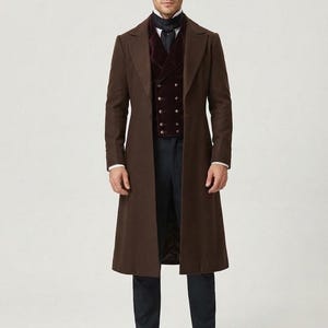 May include: A brown long coat worn over a dark burgundy double-breasted velvet vest, a white collared shirt, a dark neck scarf, and dark trousers. The text ROVIQUEAPPAREL PRECISION IN EVERY STITCH is visible in the upper left corner of the image.