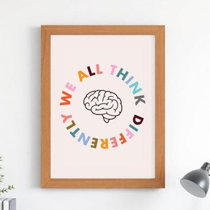May include: A framed print with a pink background and a black outline of a brain in the center. The words "We All Think Differently" are written in a circle around the brain, with each letter in a different color.