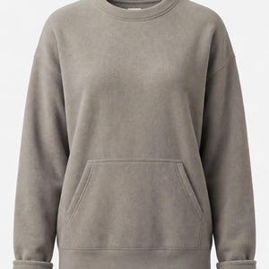 May include: A solid taupe-colored long-sleeve sweatshirt featuring a crew neckline, dropped shoulders, and a front kangaroo pocket. The garment is constructed with ribbed cuffs at the wrists and a ribbed hemline, showcasing a soft, fleece-like texture.