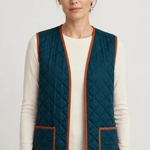 May include: A sleeveless quilted vest in a deep teal color featuring a diamond-patterned stitch. The vest is finished with contrasting brown trim along the front opening, the armholes, and the two square patch pockets on the lower front.