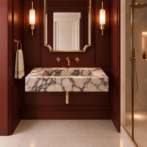 Peut inclure: Un lavabo mural en marbre blanc avec des veines gris foncé, doté d'une robinetterie dorée, d'un mitigeur assorti et de deux appliques murales verticales avec des abat-jours en verre dépoli sur des murs lambrissés bordeaux foncé.