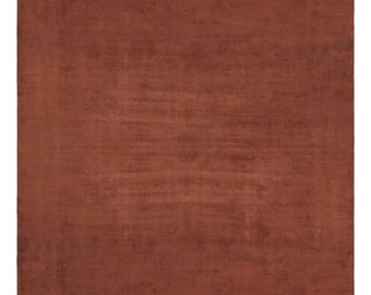 Puede incluir: Una alfombra rectangular de color rojo terracota profundo y sólido. La superficie presenta una textura sutilmente moteada con ligeras variaciones de tono, creando una apariencia suave y uniforme en toda la pieza textil tejida.