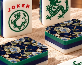 Könnte beinhalten: Vier rechteckige Mahjong-Spielsteine mit weißen, blauen und grünen Seiten. Zwei Spielsteine zeigen grüne Drachenillustrationen, einer davon mit dem roten Schriftzug JOKER. Zwei Spielsteine haben ein dunkelblaues Blumenmuster mit hellblauen Blüten.