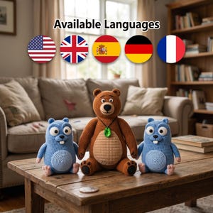 Op de afbeelding: Drie gehaakte knuffels bestaande uit een bruine beer met een groene hanger en twee lichtblauwe gopher-achtige wezens met witte tanden, allemaal geplaatst op een houten tafel met de tekst Available Languages erboven weergegeven.