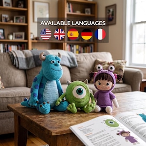 May include: Three crocheted dolls featuring a large blue monster with purple spots and horns, a small round green one-eyed monster, and a child doll wearing a purple monster costume with two eye-topped antennae, alongside an open instructional book.