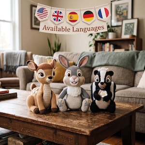 Può includere: Tre animali di peluche all'uncinetto che includono un cervo marrone e beige, un coniglio grigio e bianco e una puzzola nera e bianca che tiene un piccolo fiore bianco. Sopra di loro pende uno stendardo con cinque bandiere e il testo Available Languages.