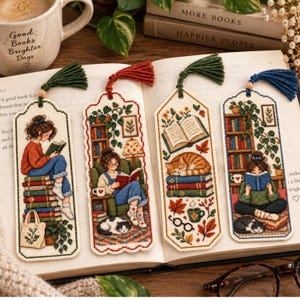 Puede incluir: Cuatro marcapáginas rectangulares de punto de cruz con escenas bordadas de personas y gatos leyendo libros. Cada marcapáginas está rematado con una borla de hilo de colores en la parte superior. Los diseños incluyen una persona sobre una pila de libros, una persona en un sillón, un gato durmiendo sobre libros y una persona leyendo con un gato cerca.