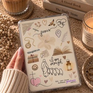 Peut inclure: Une coque de tablette transparente ornée d'un collage d'illustrations comprenant une montre de poche, un livre ouvert, une lanterne, une esquisse florale, un cœur, un oiseau et le texte "Jesus", "I am enough" et "We can never achieve greatness alone".