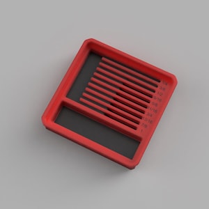 Puede incluir: Una guía de medición rectangular roja con una base interior negra. La herramienta presenta una serie de ranuras paralelas etiquetadas con fracciones imperiales que van de 1/4 a 1 pulgada, diseñadas para organizar o medir objetos.