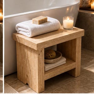 May include: A light brown stone shower bench with a rectangular top and a lower shelf. The top holds a folded white towel, a bar of soap, and a glass candle. The lower shelf contains a small bowl with a sponge and a folded white towel.