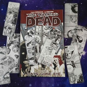 May include: A copy of The Walking Dead Volume 1 Days Gone Bye graphic novel surrounded by several rectangular bookmarks featuring black and white comic book panels with illustrations of characters and zombies from the series.