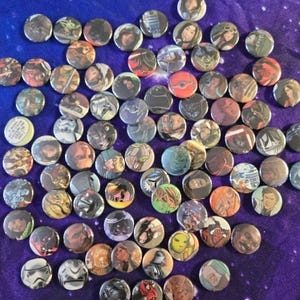 May include: A collection of round pinback buttons featuring various characters and imagery from the Star Wars franchise. The buttons are in various colors and designs, with a purple background.