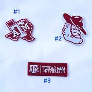 May include: Three embroidered patches featuring maroon and white designs. Patch #1 is shaped like the state of Texas with the letters ATM. Patch #2 depicts a mascot wearing a hat. Patch #3 is a rectangular label with the text TEXAS A&M UNIVERSITY.
