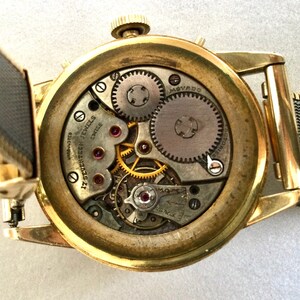 May include: A gold-toned wristwatch with a round face and a metal band. The back of the watch is open, revealing the intricate inner workings of the watch. The watch face has the text "17 SEVENTEEN JEWELS SWISS" printed on it.