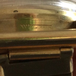 May include: A gold-toned wristwatch with a black leather band. The watch face is not visible in the image. The watch has the word "Waltham" engraved on the side.